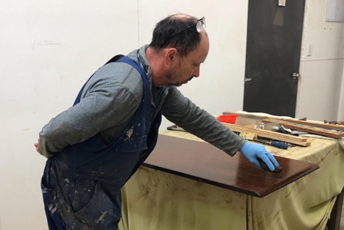 Tony Kilmister from Kilmsiter Furniture Restoration using tradition French polishing technique on a wooden table top.