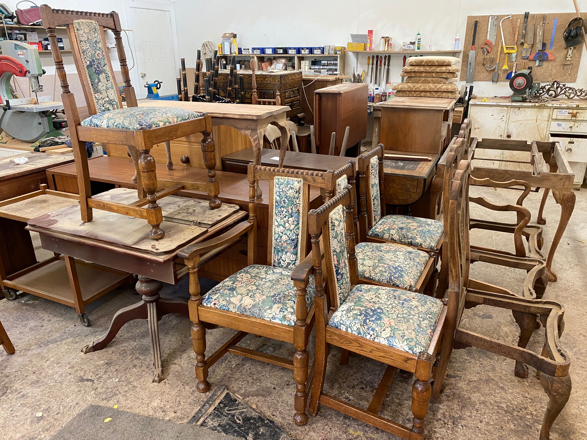 A collection of furniture that is in the process of being restored and repaired in the Kilmister Furniture Restoration workshop.