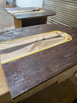 Boardroom table top that has been covered in stripper and it taped up as part of the restoration and repolishing process at Kilmister Furniture Restoration.