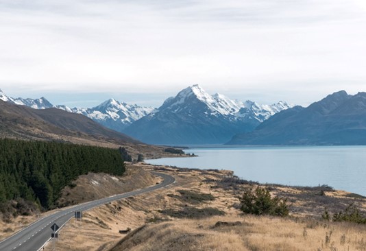 Beautiful country road with stunning landscape backdrop in New Zealand.
