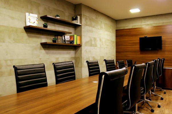Wooden boardroom table and chairs surrounded by black leather chairs.