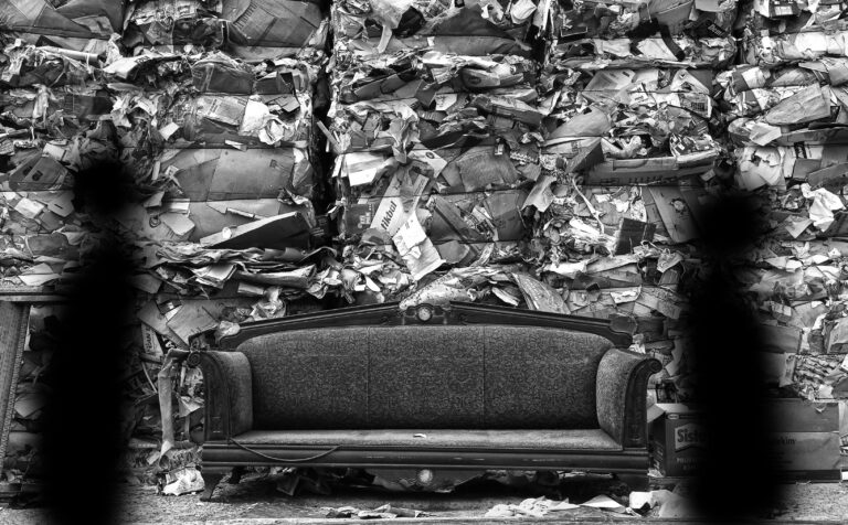 A large couch that has been discarded sitting in a landfill.